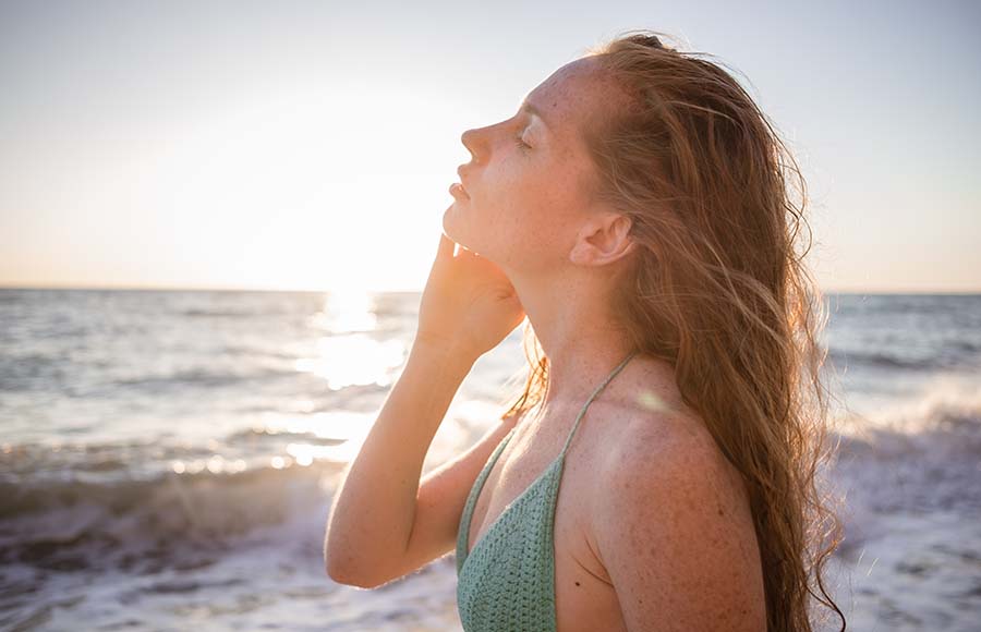 Mujer con los ojos cerrados en la playa