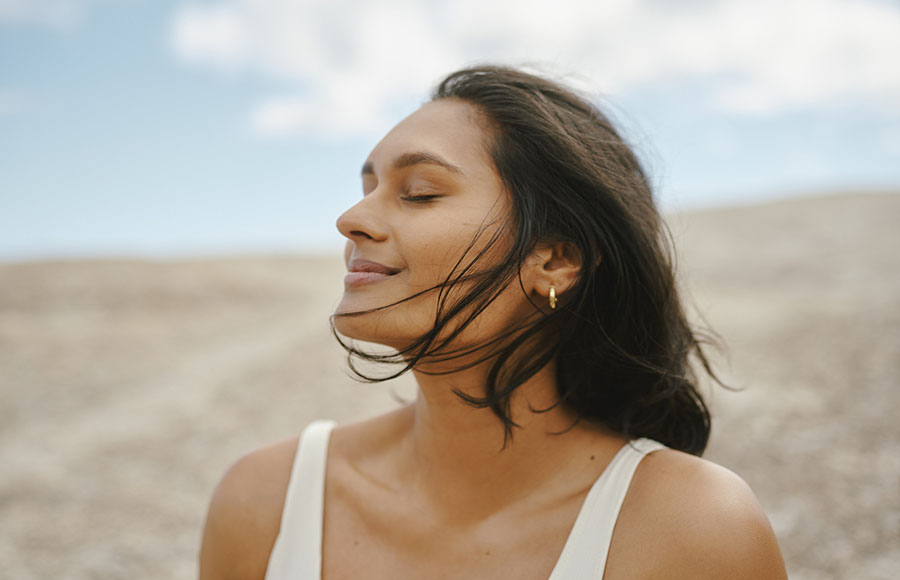 Mujer con los ojos cerrados disfrutando de la playa