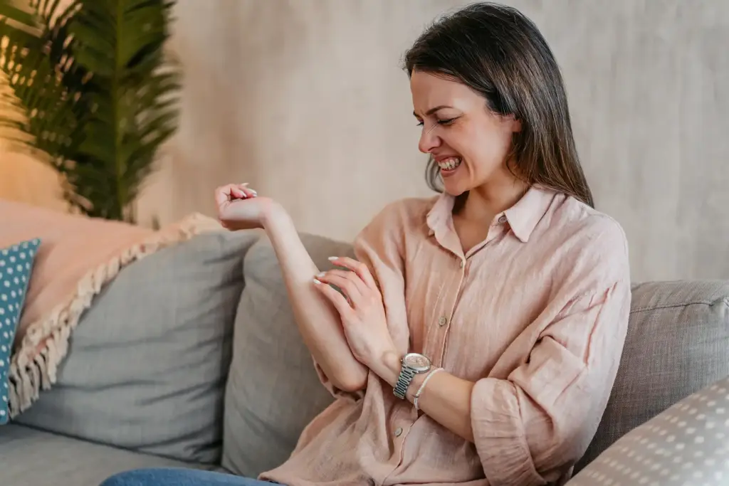 Dona rascant-se els braços per irritacions