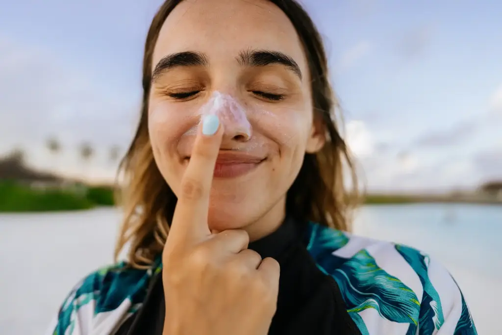 Mujer en la playa con crema solar en la nariz